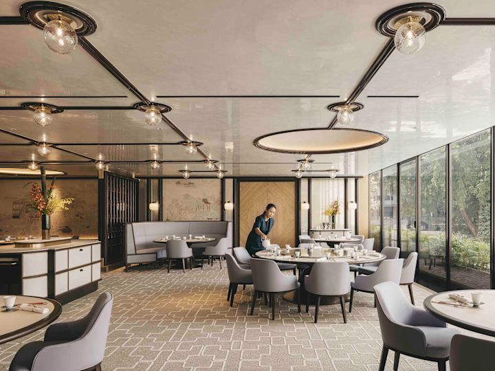 Hotel Summer Palace z członkiem personelu oraz wieloma okrągłymi stołami i krzesłami