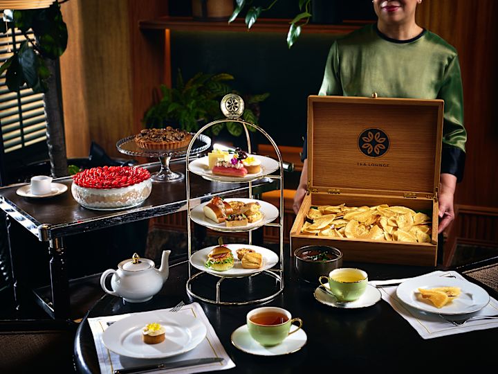 Personne tenant une boîte en bois au salon de thé avec collations et douceurs