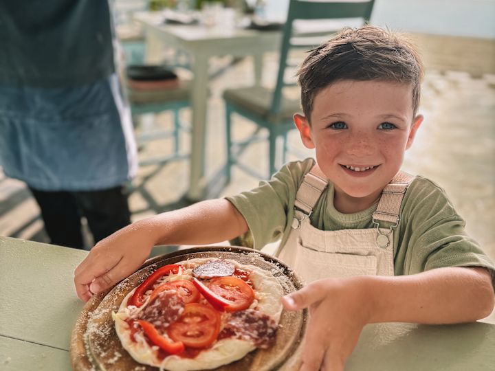 Dítě se učí vyrábět pizzu na pláži