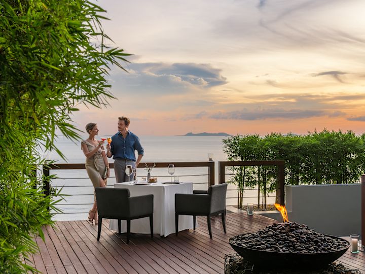 Couple dining on the terrace of Jahn restaurant with beach view at sunset