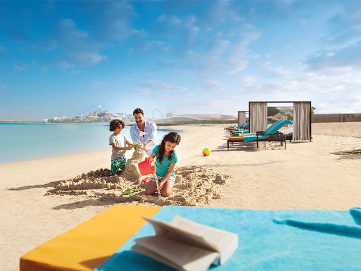 Дети играют в песке с отцом на пляже