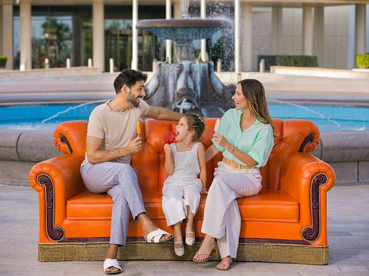 Familie auf orangefarbenem Sofa im Freien