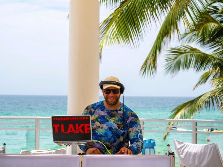 Arka planda deniz bulunan bir podyumda duran DJ