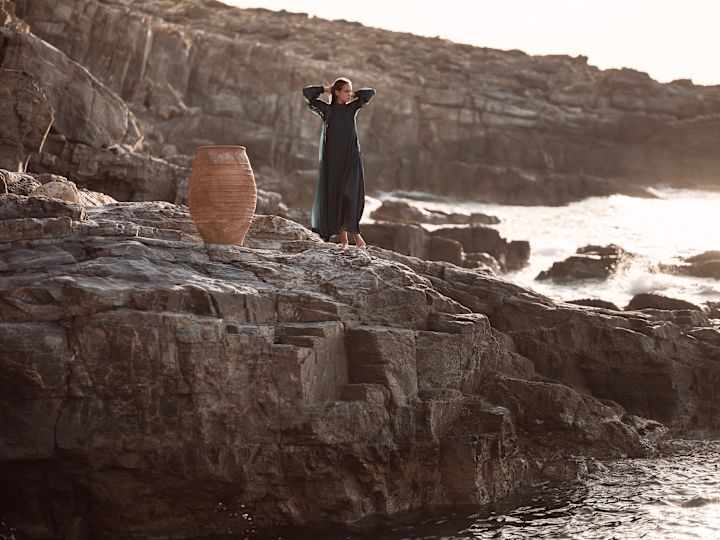 une femme debout sur un rocher au bord de la mer