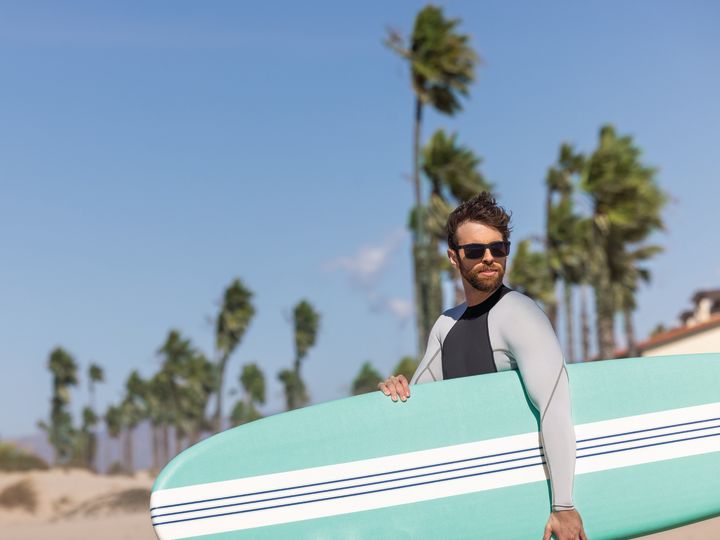 Man Holding a Surfboard at the Beach