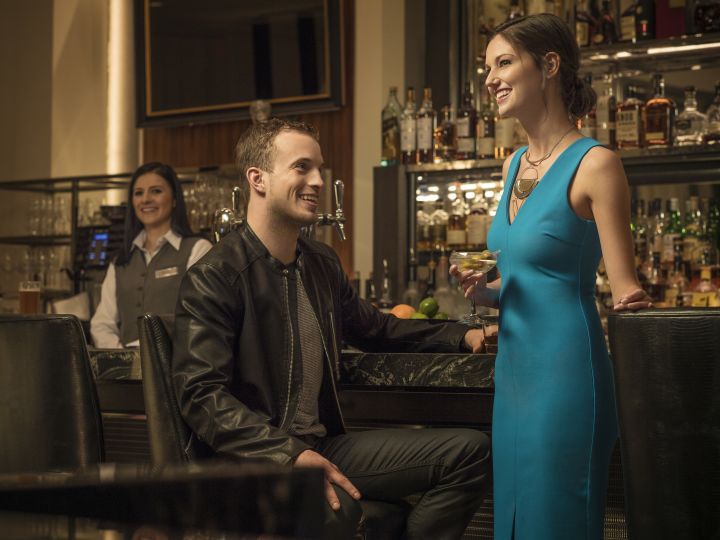 couple smiling at a bar with bartender