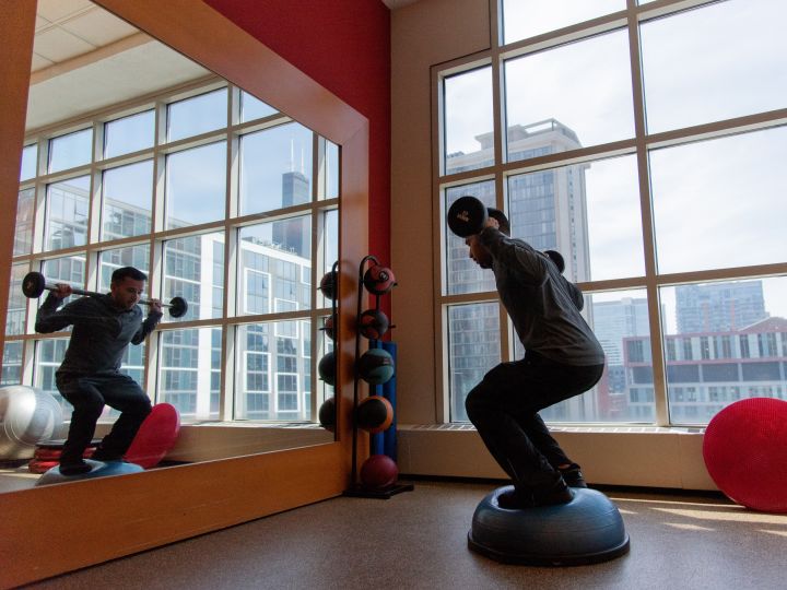 Man Exercising in Fitness Center with Large Windows and City View