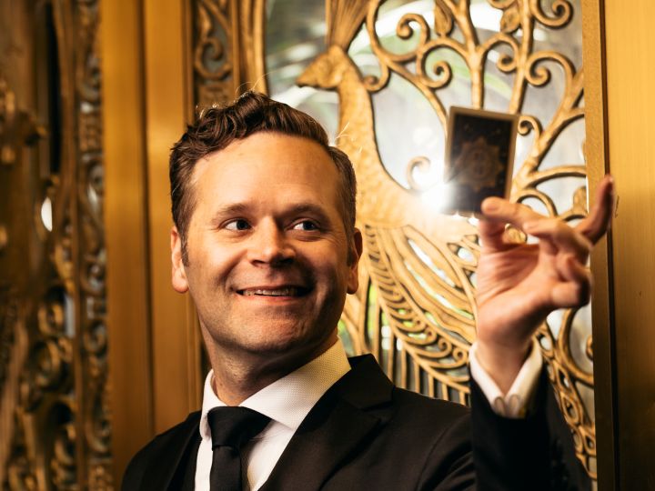 Zaubergeister und Entertainer Dennis Watkins hält eine Karte