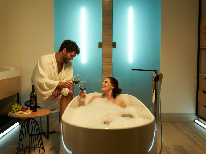 Couple having wine in bathroom with tub