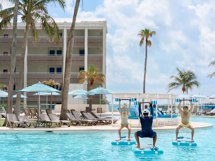 Man and woman participating in water exercise class with trainer.