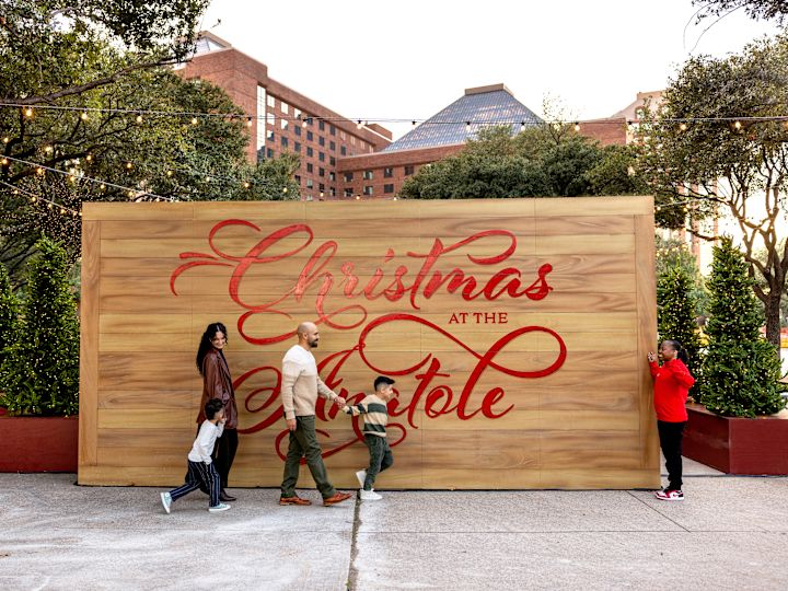 People Standing next to a Christmas at the Anatole Sign