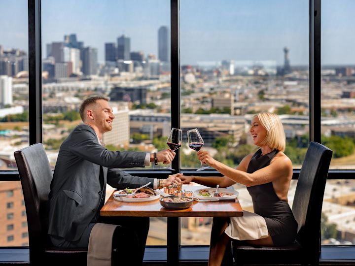 Couple dining at SER Steak + Spirits restaurant with panoramic city views
