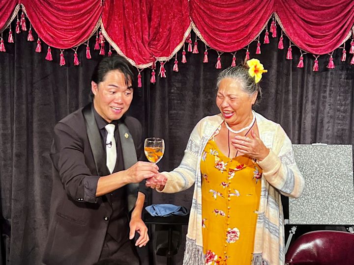 espectáculo de magia mago y voluntario sosteniendo un vaso de agua con pez dorado