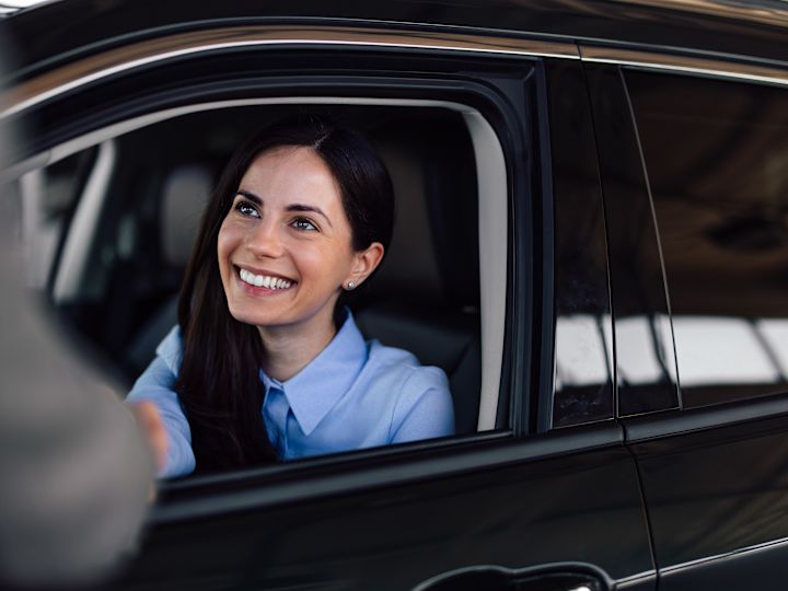 a Woman in a Car Shakes Hands with a Man Welcoming Her to the Hotel