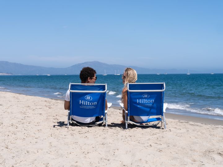 Couple Sitting on Lounge Chairs Talking at the Beach
