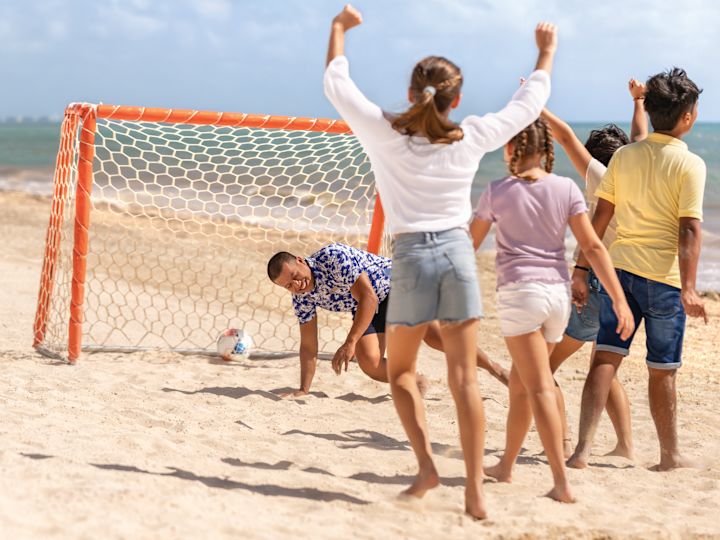 Children cheer and play soccer on the beach