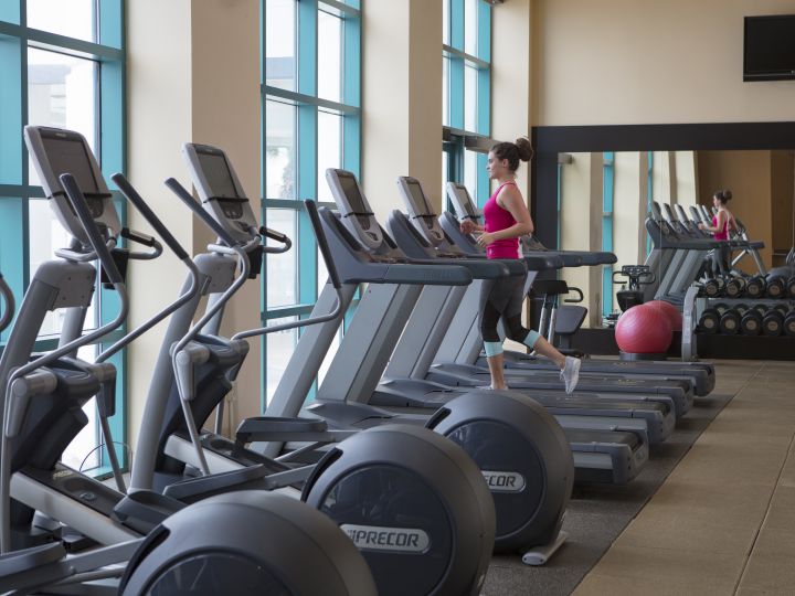 Fitness Center with Cross-Trainers, Treadmills, Gym Ball and Woman Running on Treadmill