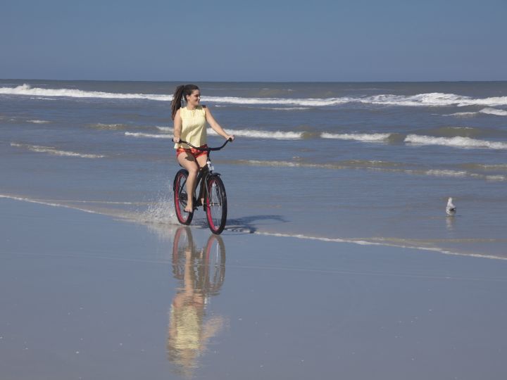 Woman Cycling Along Beach at Daytime