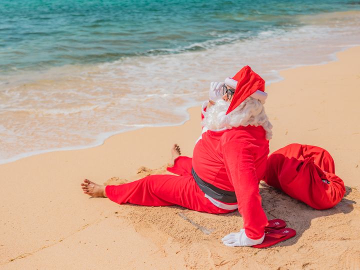 Santa sitting on the beach by the water