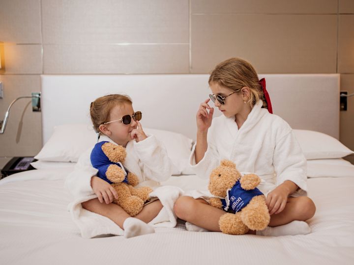 Enfants portant des peignoirs sur un lit avec des lunettes de soleil et des ours sur le thème Hilton