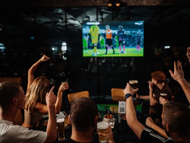 people watching sports game on tv at bar