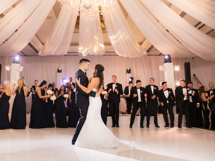 Bride and groom dancing on ballroom floor surrounded by guests