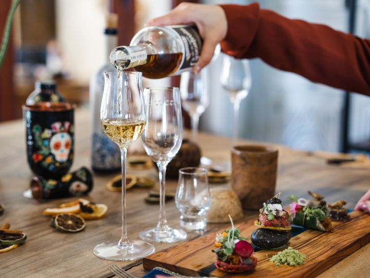 Gießen eines Getränks in ein Glas am Tisch mit Vorspeisen