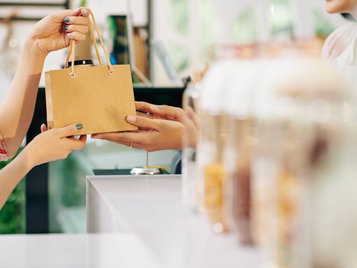 Person grabbing a bag at the checkout counter