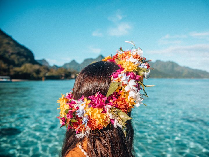 青い海を眺めながら、明るい色の花冠を身につけた女性