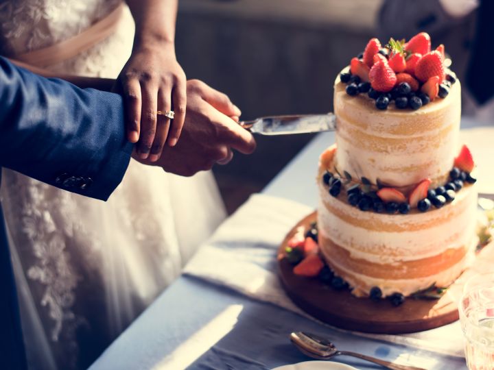 Bride and groom cutting cake topped with strawberries