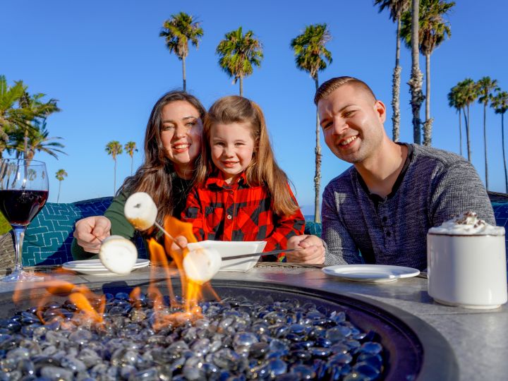Family roasting marshmallows on a fire pit
