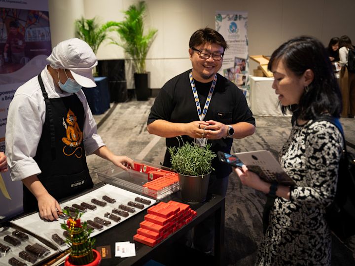 Local partnerships sustainability image with person serving food in event space with two people talking