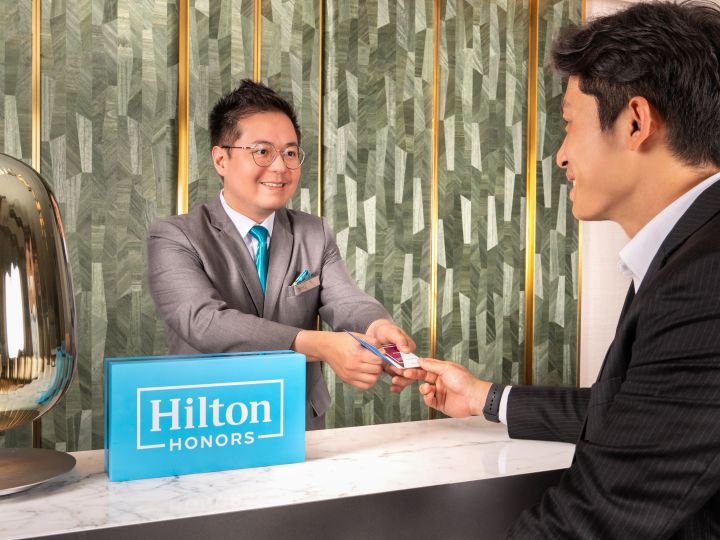 Shot of staff at reception desk handing key to guest