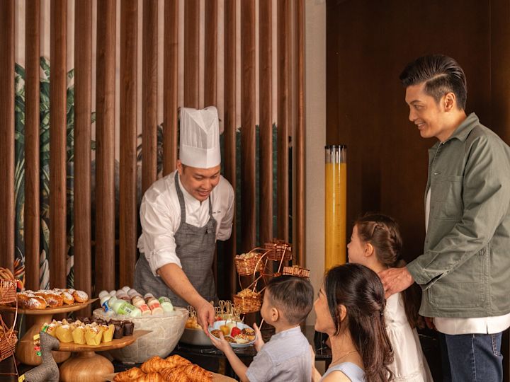 Chef giving kid dessert with family in front of dessert buffet