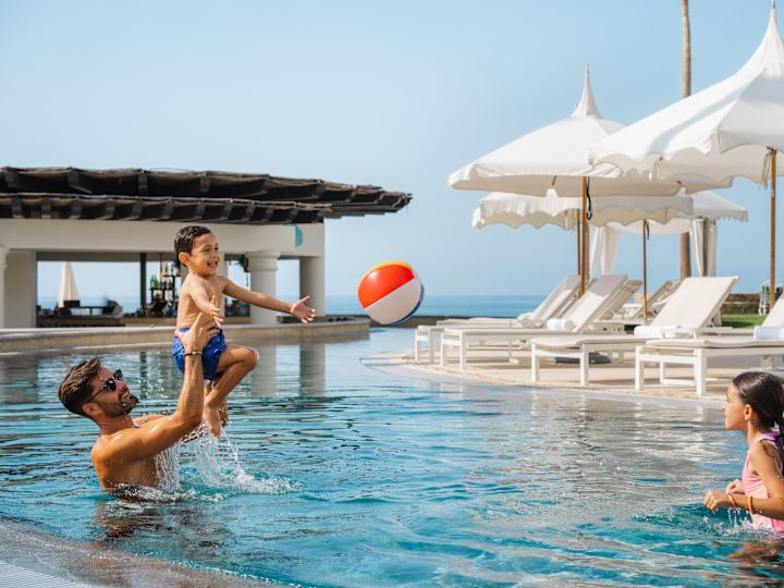 family playing in outdoor pool