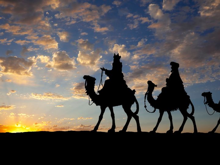 Arkasında güneşin olduğu develerin arkasında üç adamdan oluşan siluet