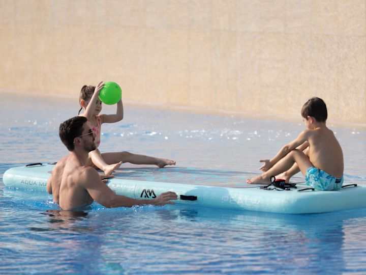 Une famille jouant au ballon sur un bateau gonflable à la piscine