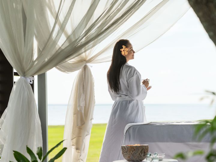 Woman looking out to sea view from outdoor spa area
