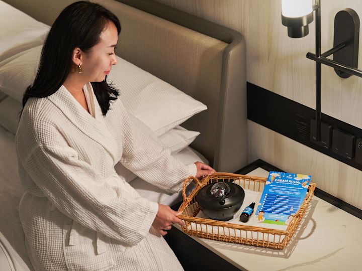Woman in a Hotel Room Holding a Basket with a Dream Ritual Kit