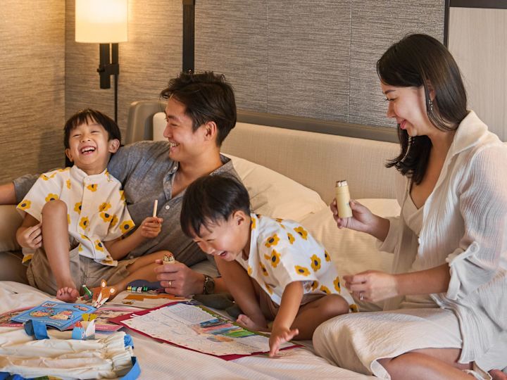 Family Enjoying Time Together on a Bed in a Hotel Room