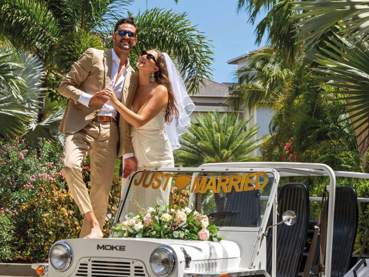 Couple standing on just married jeep
