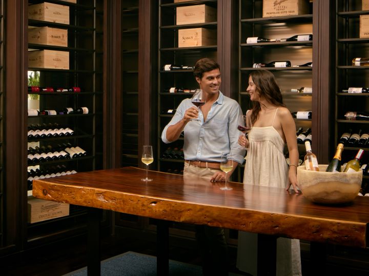 Man and woman in wine room, holding glasses of wine
