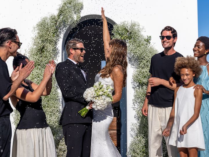 Konfeti etraflarına düşerken gülümseyen düğün kıyafeti giyen adam ve kadın ve diğer insanlar