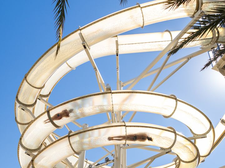 Persone su uno scivolo d'acqua nella piscina esterna