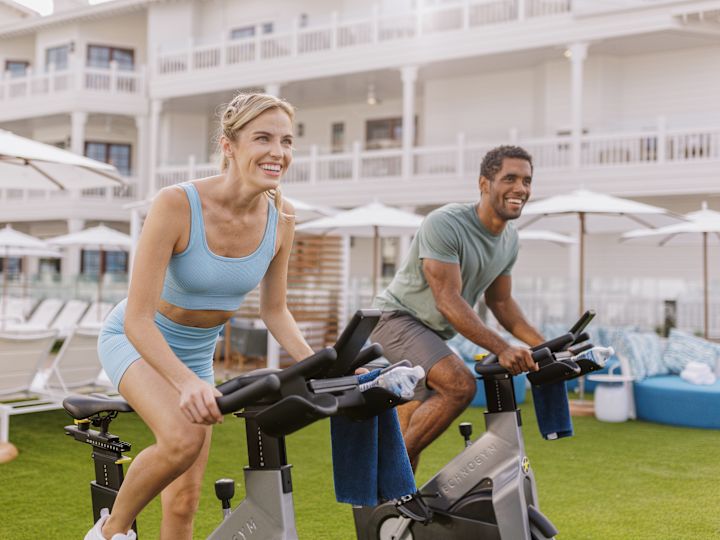 man and woman outdoors using stationary bikes