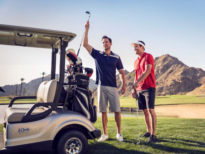 Two golfers getting clubs out of golf cart