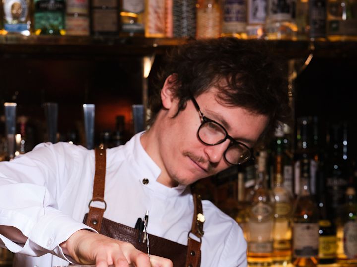 Bar staff pouring cocktail behind bar