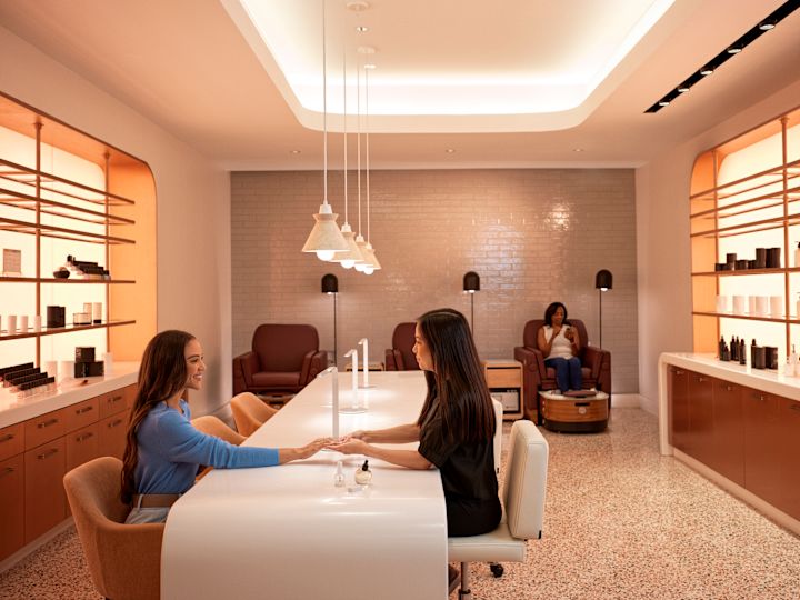 Woman receiving beauty treatment as another woman relaxes on chair