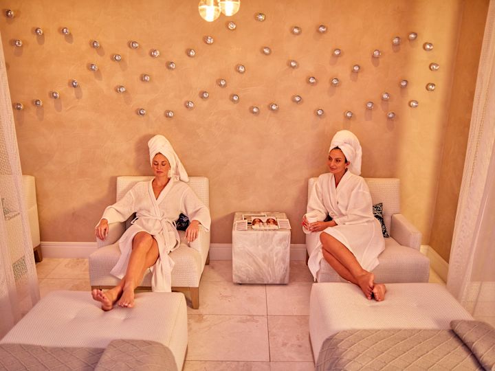Două femei relaxându-se în spa cu halate și prosoape albe