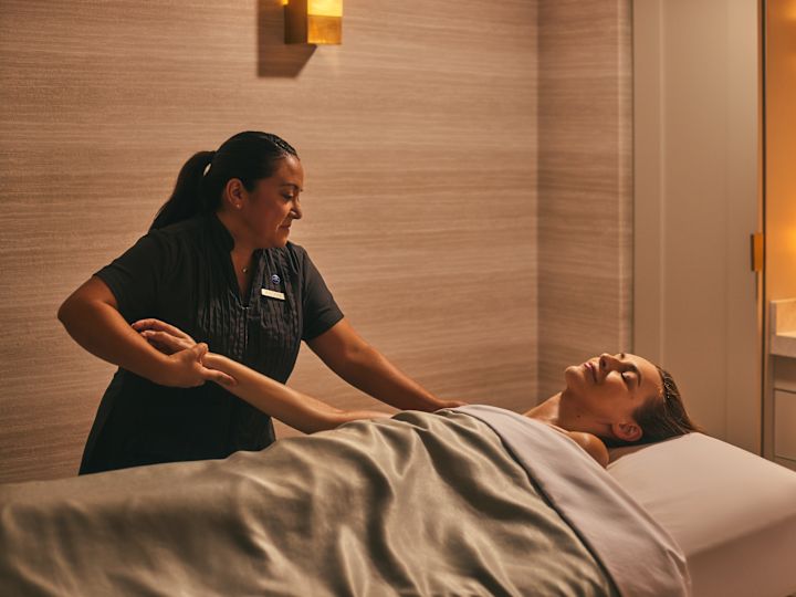 Woman in spa treatment room receiving massage from masseuse